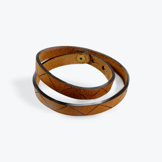 Brown leather wood-burned pyrography bracelet with a white interior on a white background